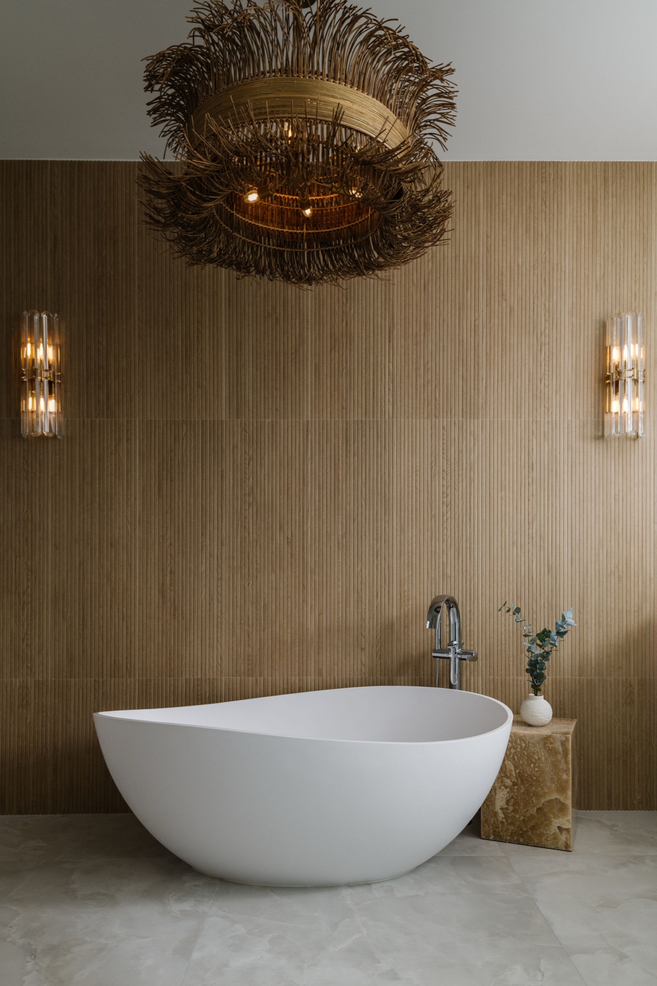 Spa-like bathroom by Oak Heart Interiors with a sculptural freestanding tub, fluted wood wall and a woven chandelier, featured in Martha Stewart