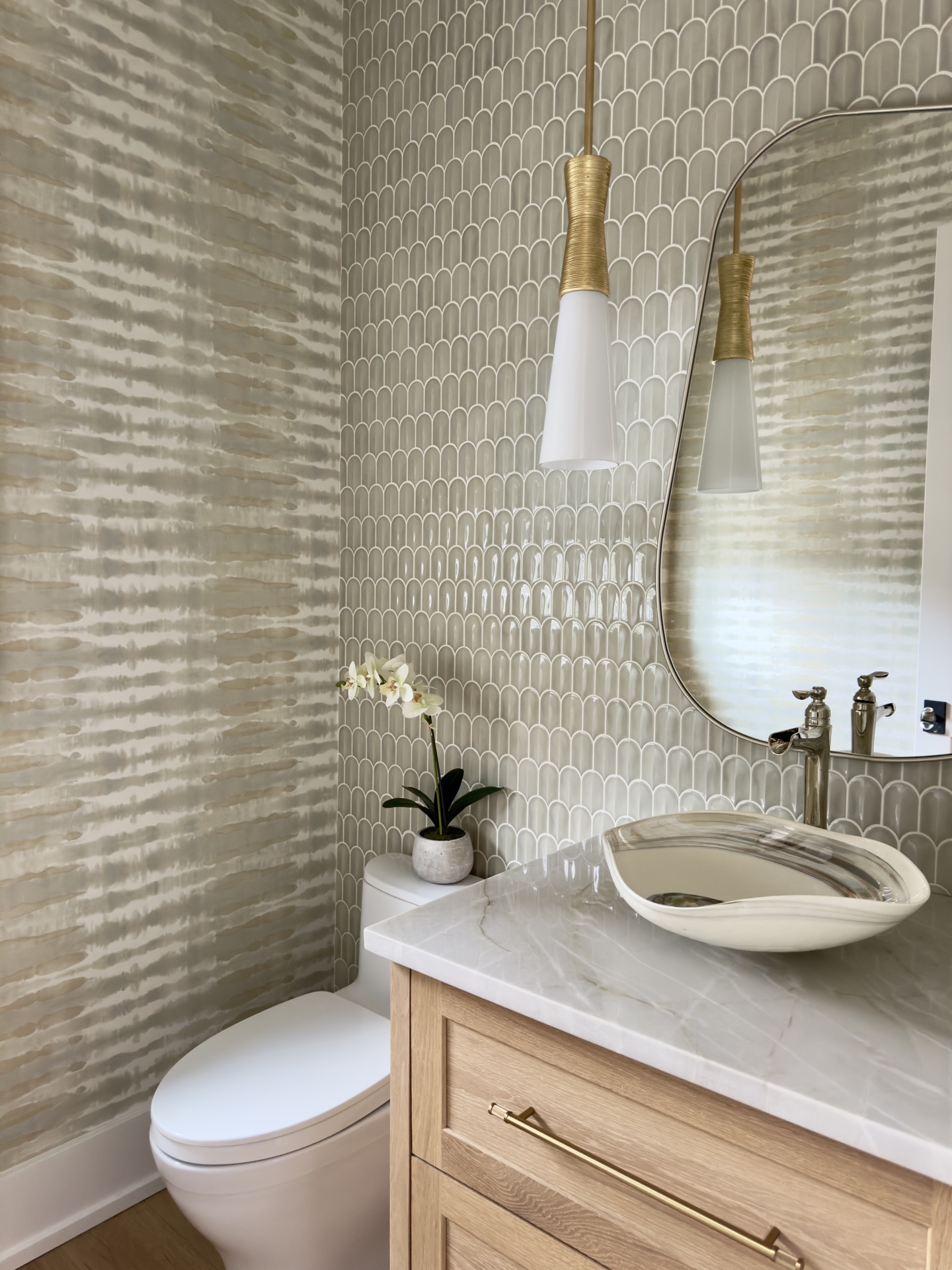 Elegant powder room with scalloped tile, a white oak vanity and a sculptural vessel sink by Oak Heart Interiors
