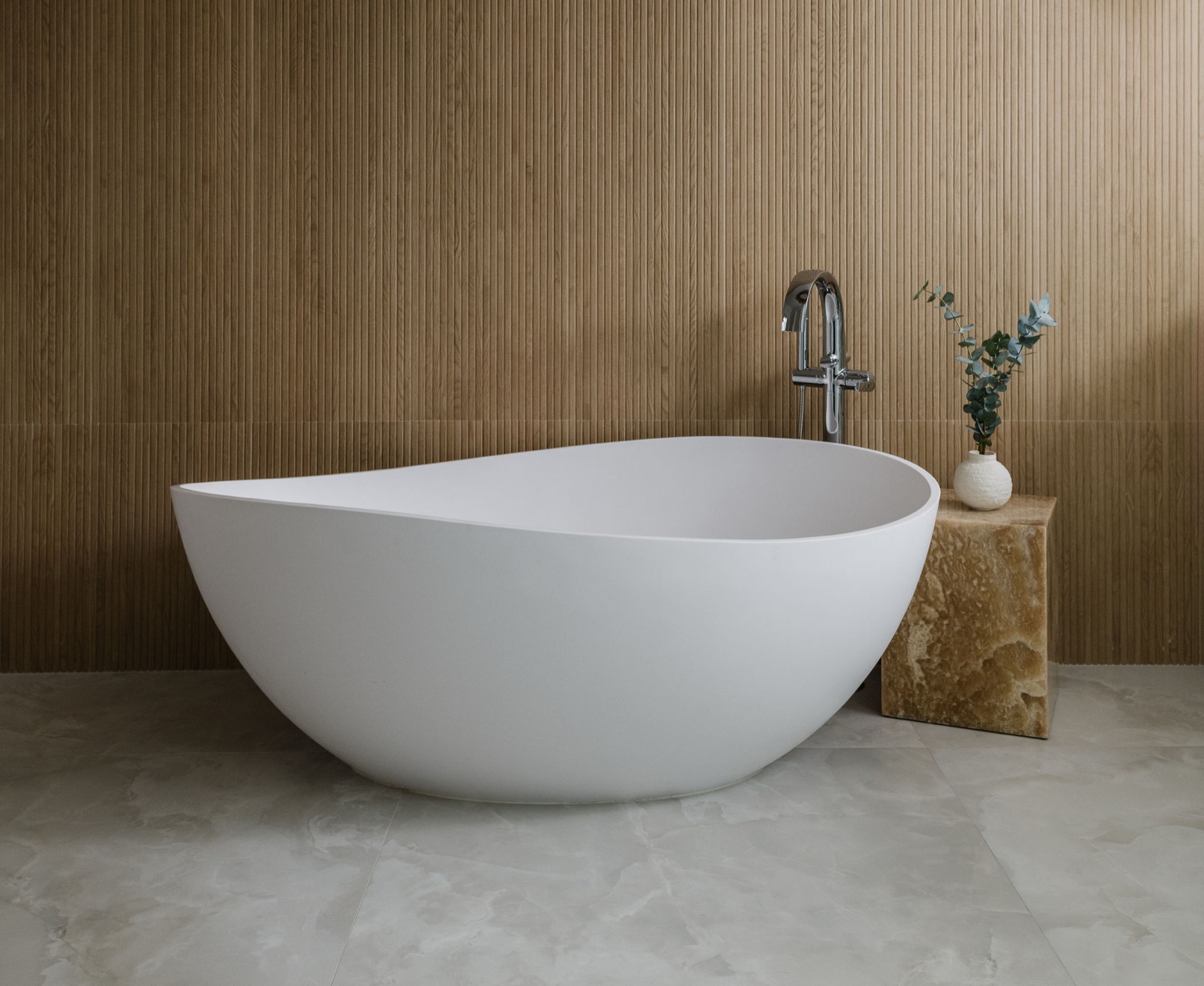 Sculptural freestanding tub against a fluted wood wall with a stone side table in a Luxurious Bathrooms project by Oak Heart Interiors