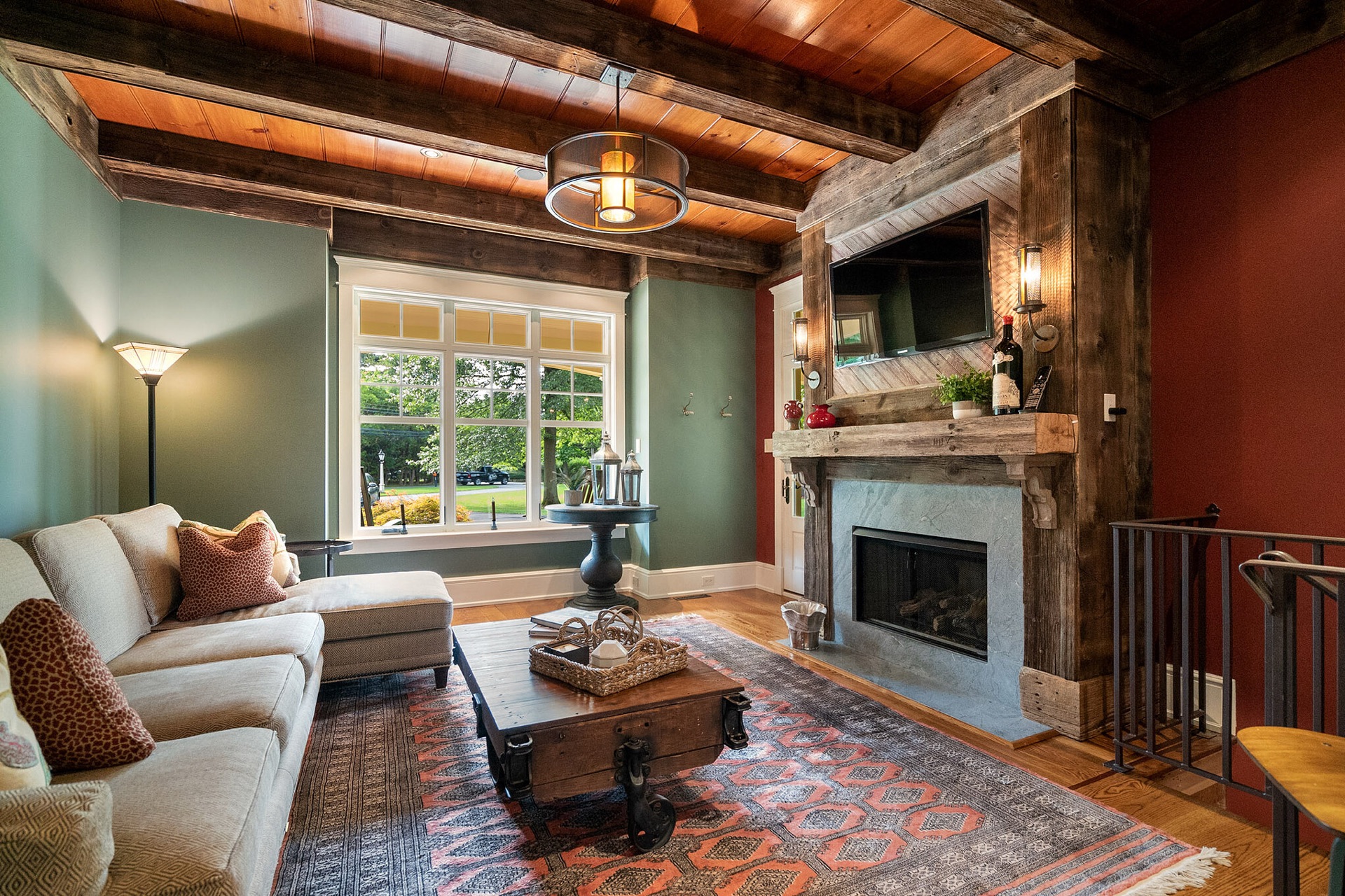 Magnifica living room with reclaimed wood ceiling beams, a stone fireplace and warm sage and terracotta tones