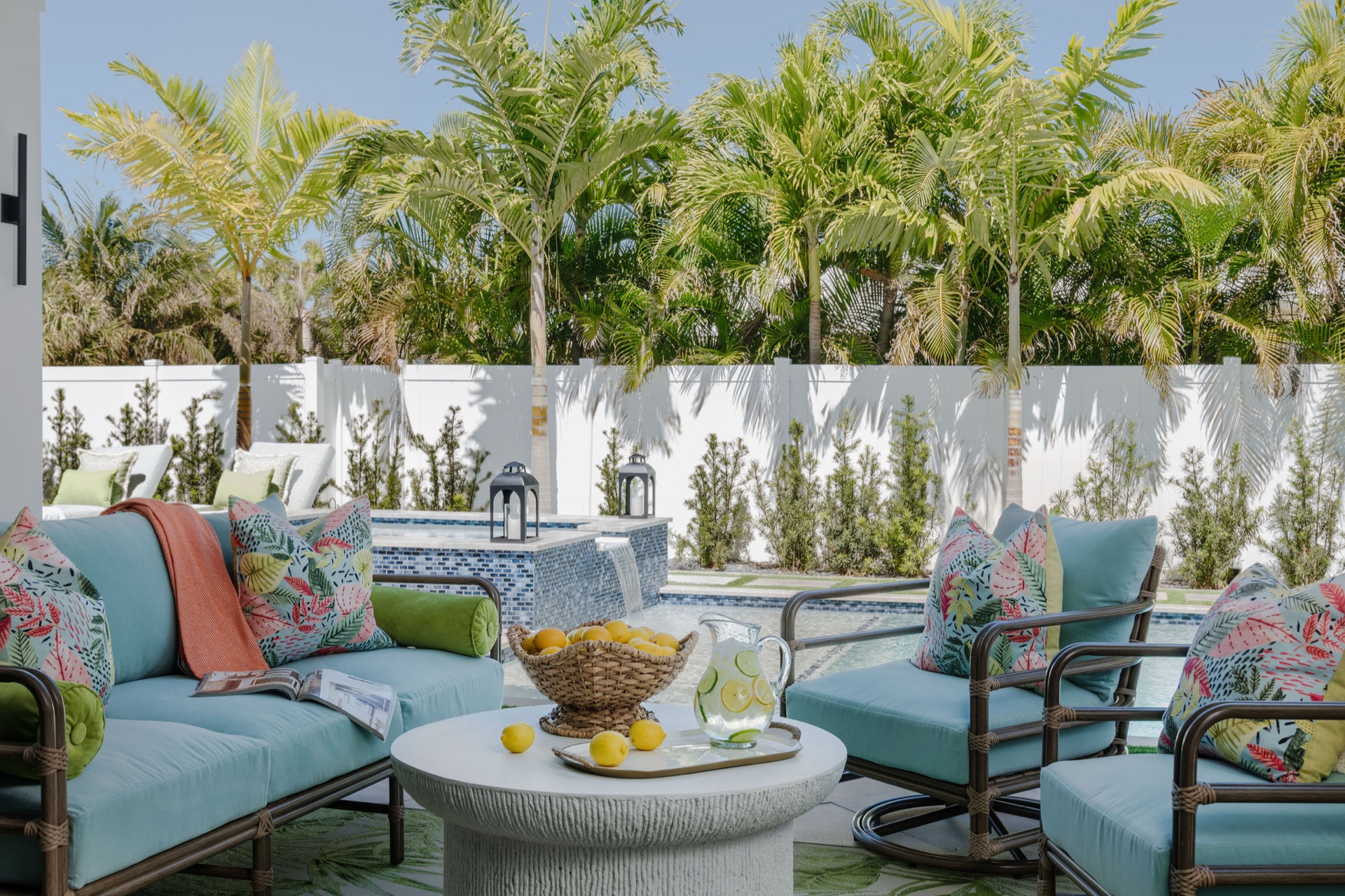 Vivere Luxe outdoor living space with palm trees, a pool and turquoise cushioned seating